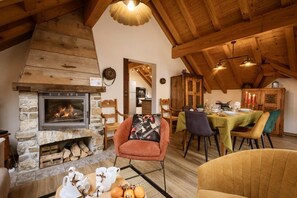 A cozy interior with a stone fireplace, wooden beams, a dining area, and a living space with a sofa and chairs. - 350m from shops, 1st floor, fitness, sauna, hammam, balcony, fireplace or stove, ski locker, 55m² (Valloire)