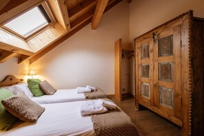 A room with two beds, a skylight, and a wooden wardrobe with intricate carvings. - 350m from shops, 1st floor, fitness, sauna, hammam, balcony, fireplace or stove, ski locker, 55m² (Valloire)