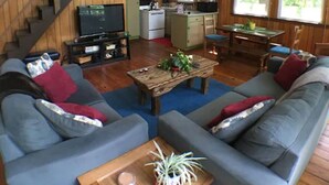 A spacious living area with a grey sofa set, a wooden coffee table, and a staircase leading to an upper level.