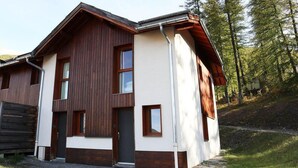 Una casa de madera de dos pisos con fachada blanca, una puerta principal y un pequeño porche.