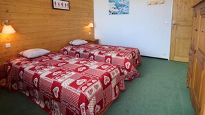 A room with two beds, wooden walls, a door, and a painting.