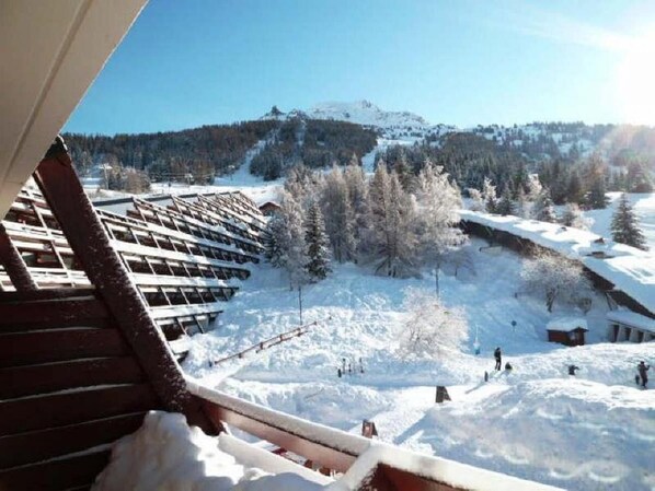 A snowy outdoor area with a wooden structure, possibly a ski lift, and a mountainous background.