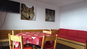 A dining area with a wooden table and chairs, a red sofa, and two wall-mounted animal paintings. - 50m from ski lifts, 4th floor, view mountain, balcony, tv, 30m², Les Arcs (Les Arcs)