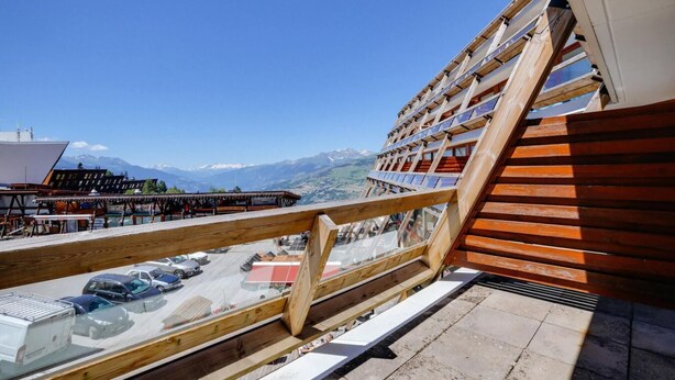 A balcony with a wooden railing overlooking a parking area and a mountain view. - 50m from ski lifts, 4th floor, view mountain, balcony, tv, 30m², Les Arcs (Les Arcs)