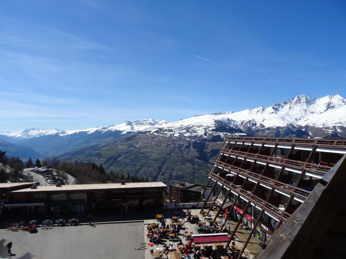 A mountain resort with a ski lift, a dining area, and a view of snow-capped peaks.