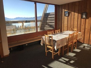 A dining area with a table and chairs, a bench, and a large window with a view of mountains.
