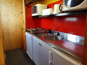 A compact kitchen with a sink, stove, and microwave.