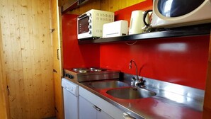 Een kleine keuken met een spoelbak, kookplaat en magnetron.