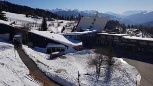 Een wintersportgebied met gebouwen onder de sneeuw en een berg op de achtergrond.