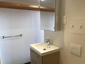 A bathroom with a white sink, a mirror, a towel rack, and a light switch.