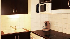A compact kitchen with dark cabinets, a white sink, a microwave, a stove, and a dishwasher. - Ski-in/ski-out & foot of the slopes, 1st floor, view swimming pool, swimming pool, sauna, hammam (Les Orres)