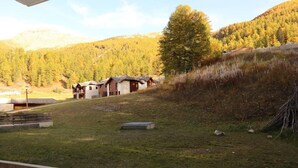 A hillside with a row of cabins and a large tree. - Ski-in/ski-out & foot of the slopes, 1st floor, view swimming pool, swimming pool, sauna, hammam (Les Orres)