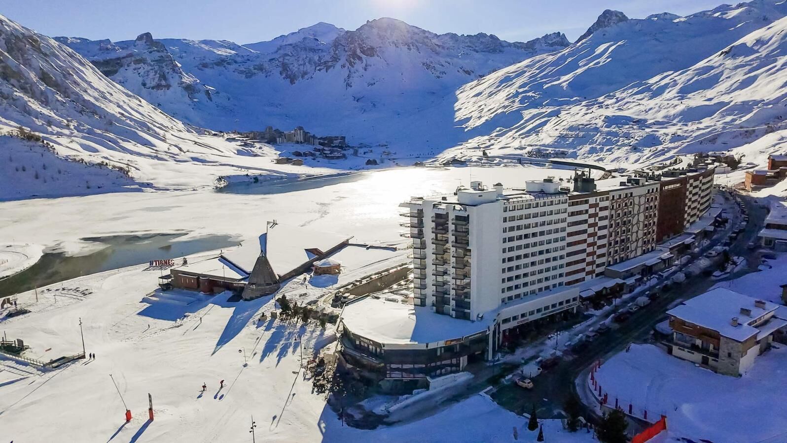 A snow-covered mountain resort with a large hotel and a heliport.
