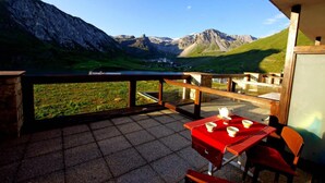 Une terrasse avec une table et des chaises, offrant une vue sur un paysage montagneux.