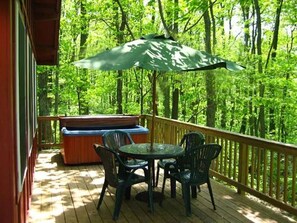A wooden deck with a table and chairs, a hot tub, and a large umbrella. - Bedrooms 2, Bathrooms 1, Sleeps 4 (Linden)