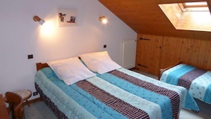 Ein Zimmer mit zwei Betten, Holzwänden, einer geneigten Decke und einem Dachfenster.