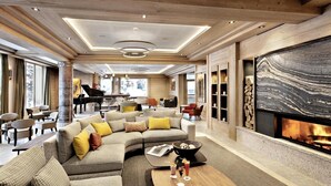 Un vaste espace de vie agrémenté d’un magnifique piano à queue, de sièges confortables, d’une cheminée et d’une grande œuvre d’art abstraite accrochée au mur.