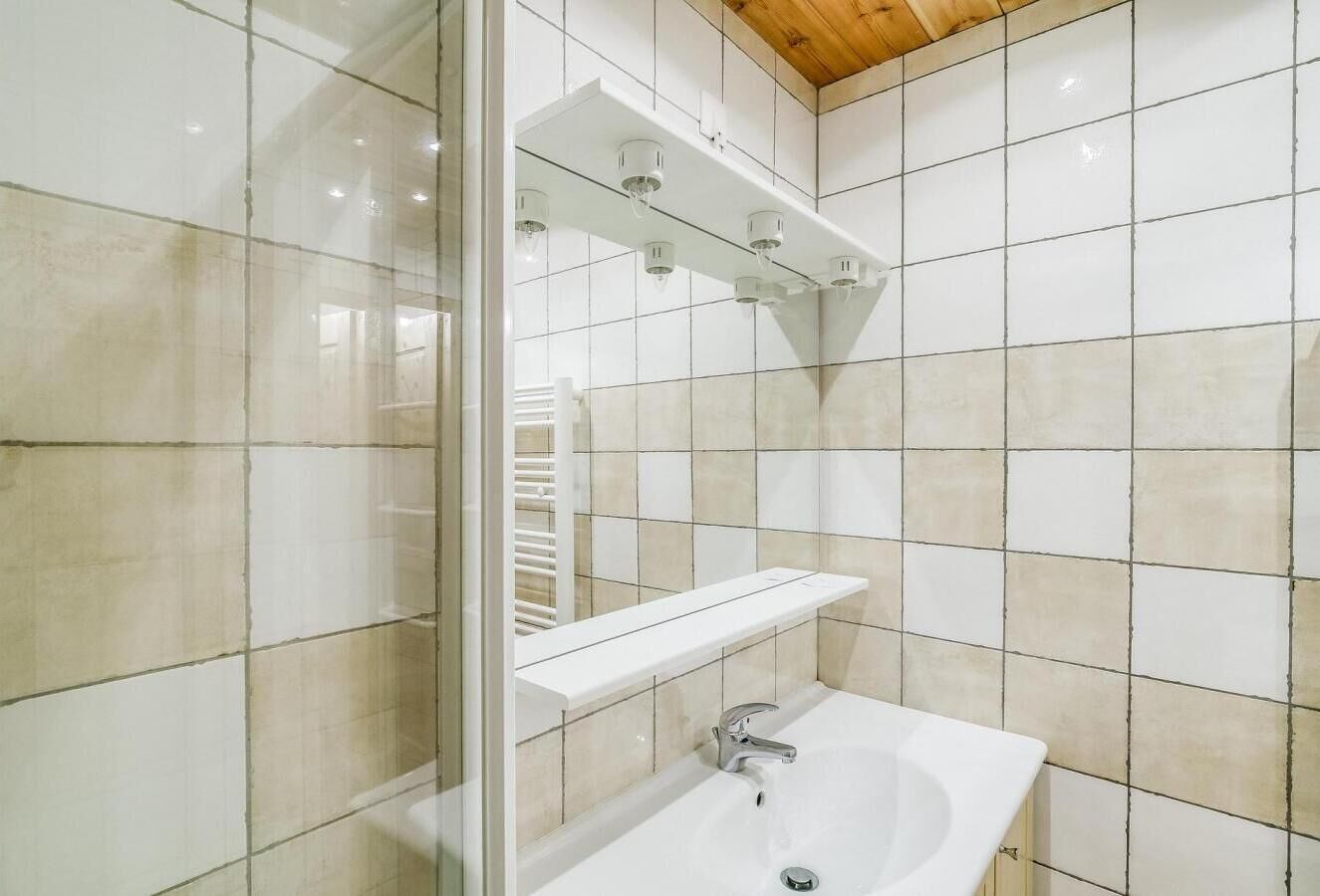 A modern bathroom with a glass shower enclosure, a white sink, and a mirror above the sink.