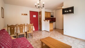 A compact living space with a dining area, kitchenette, and a television mounted on the wall. - 10m from ski slopes, 1st floor, balcony, tv, ski locker, 40m², Val Cenis (Lanslevillard)