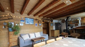Una habitación acogedora con techo de madera, un sofá, una mesa de comedor y una zona de cocina.