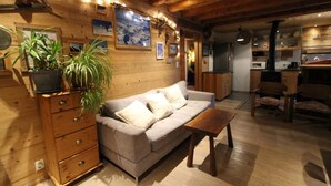 Una sala de estar acogedora con un sofá, armarios de madera, una mesita de centro y una planta en maceta.