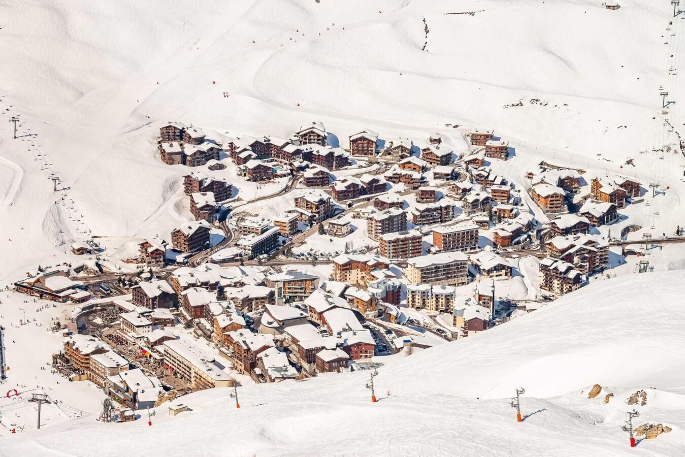 Une station de ski enneigée, dotée de plusieurs chalets et d’un télésiège.