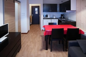 A compact living space with a dining area, kitchenette, and a television on a dresser.