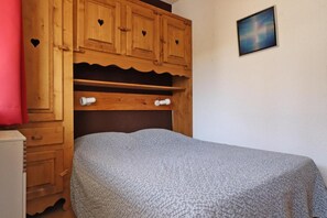 A bedroom with a bed, wooden wardrobe, and a wall-mounted artwork. - 150m from ski slopes, 1st floor, balcony, 38m², Méribel-Mottaret (Méribel - Les Allues)
