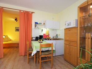 A compact kitchen with a dining area, a bed, and a cabinet.