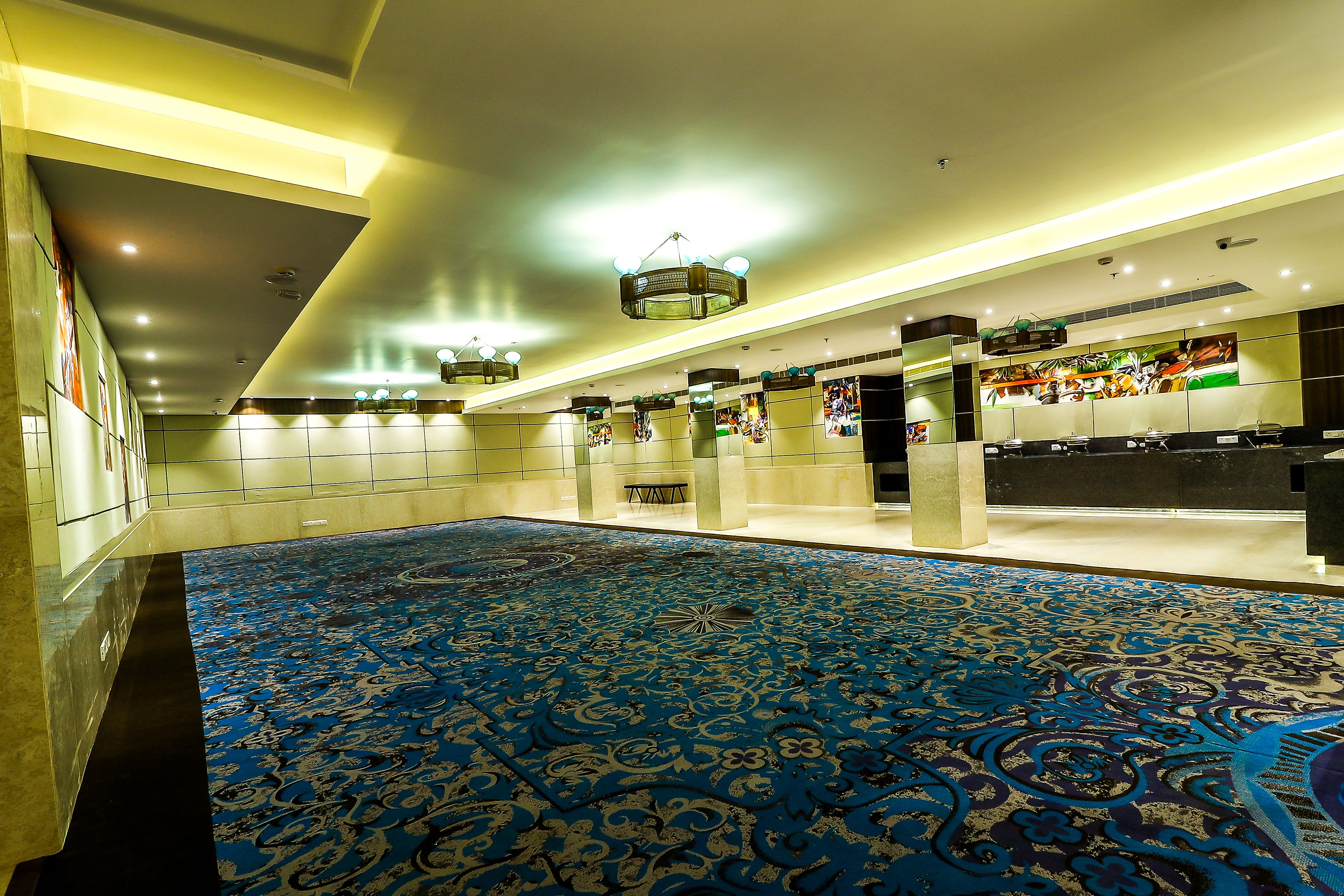 A spacious lobby with a patterned carpet, recessed lighting, and a modern chandelier.