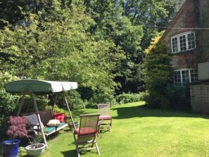 A garden with a swing set, two chairs, and a lawn. - Bridge Cottage B & B (Midhurst)