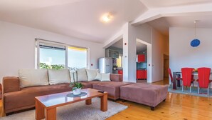 A modern living room with a sectional sofa, a wooden coffee table, and a dining area with red chairs. - 3 bedroom stunning apartment in Rogotin (Rogotin)