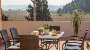 A balcony with wicker chairs and a table set for a meal, overlooking a scenic landscape with trees and distant hills. - 3 bedroom stunning apartment in Rogotin (Rogotin)