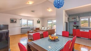 A spacious living area with a dining table, red chairs, a sofa, and a kitchen area with red cabinets. - 3 bedroom stunning apartment in Rogotin (Rogotin)
