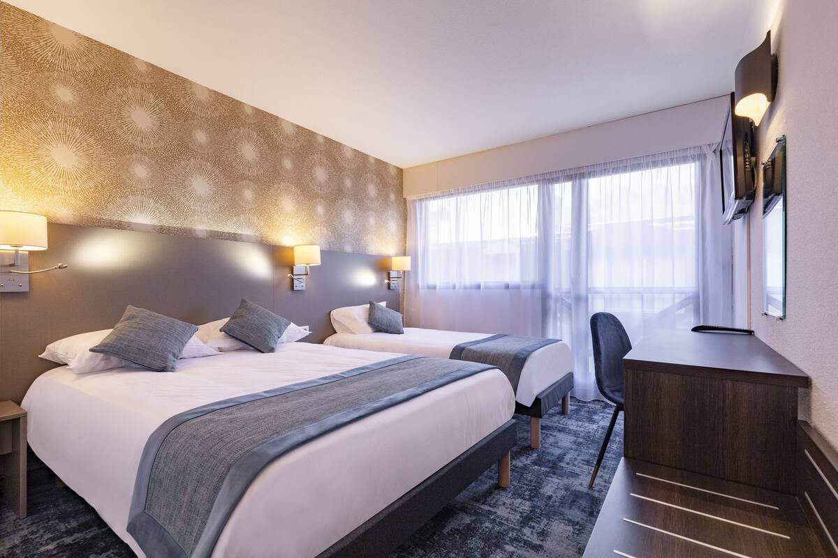 Habitación de hotel con dos camas, un escritorio y una silla.