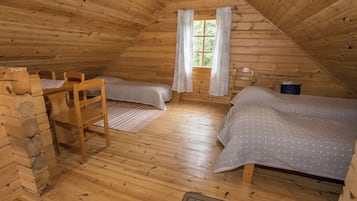 A cozy attic bedroom with two beds, a wooden chair, and a window with curtains.