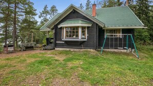 A cabin with a green roof, a porch, and a swing set. - Kotkanpesä by Interhome (Masku)