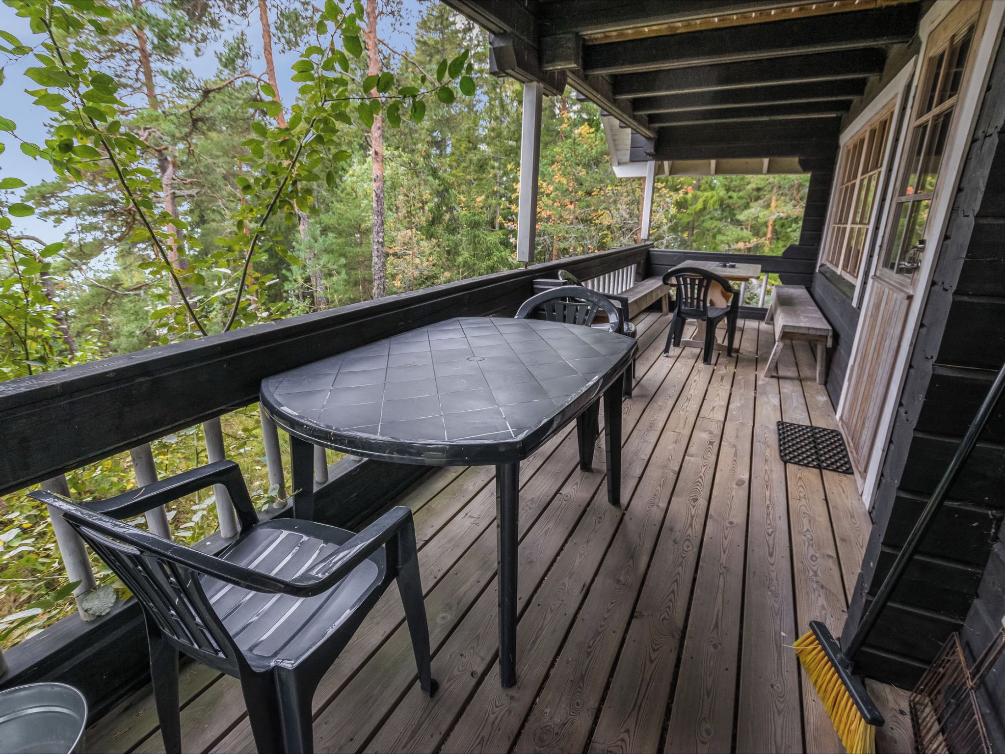 A wooden deck with a table and chairs, overlooking a forested area.
