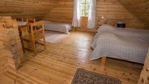 A cozy attic bedroom with wooden walls and sloped ceilings, featuring two beds, a wooden chair, and a small table. - Kotkanpesä by Interhome (Masku)