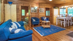 Un interior de cabaña acogedor con un sofá azul, una pequeña mesa redonda y un comedor.