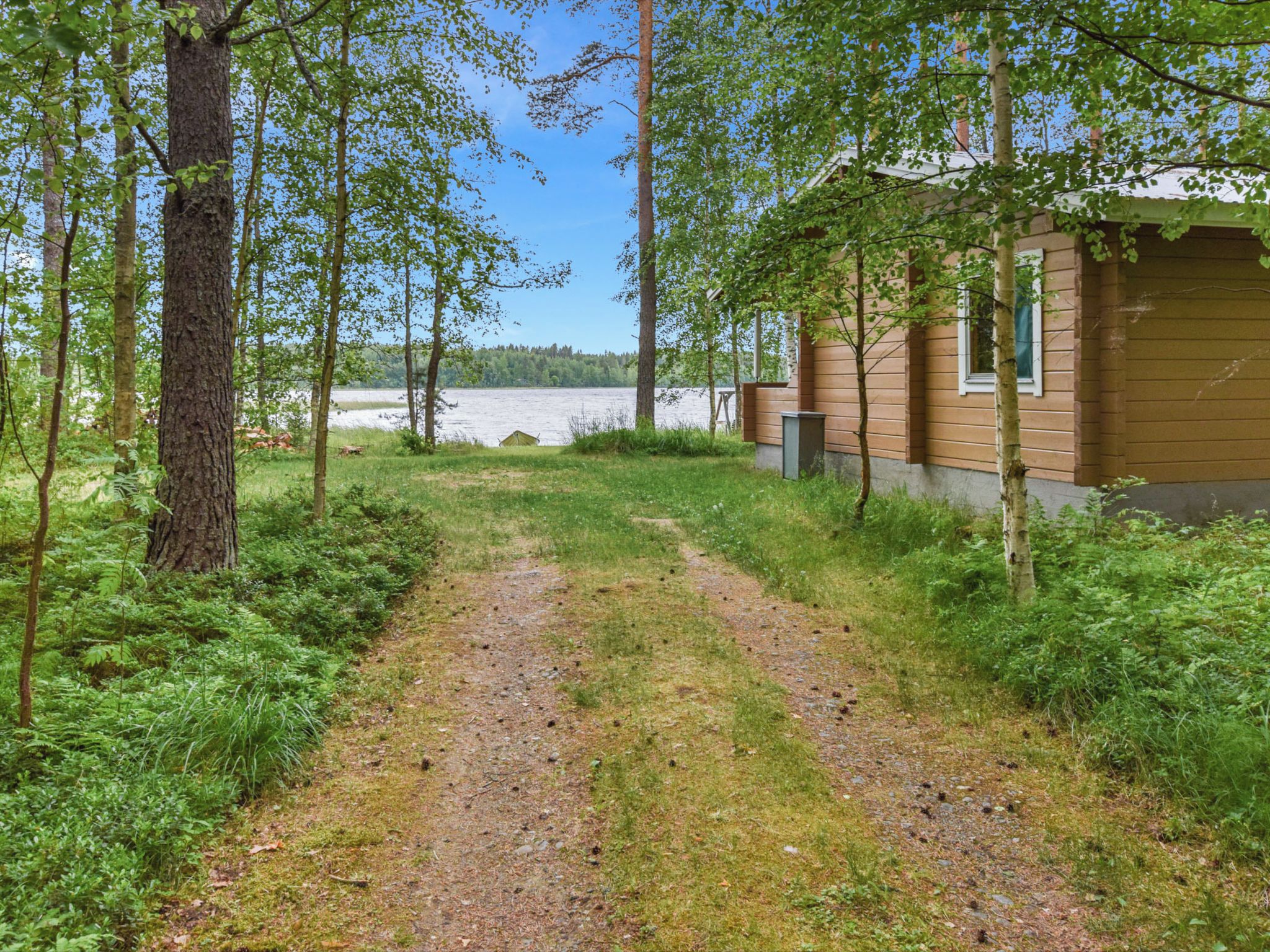 Un sentier de gravier menant à un chalet avec vue sur le lac.