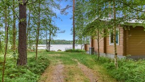 Una cabaña junto a un lago, con un sendero de grava que la conduce.