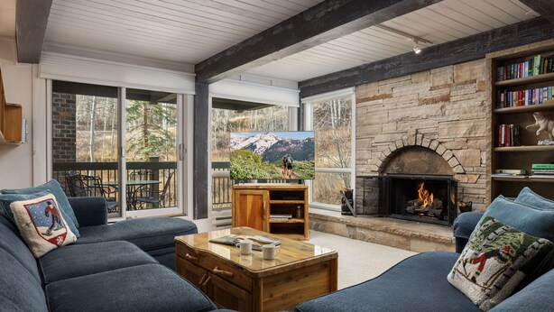 A cozy living room with a fireplace, large windows, and a comfortable seating area. - Top of the Village~Ski-in/out~HT~Pool~Grill~Parking (Snowmass Village)