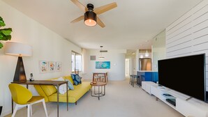 Un salon moderne avec un canapé jaune, une table à manger et un téléviseur.