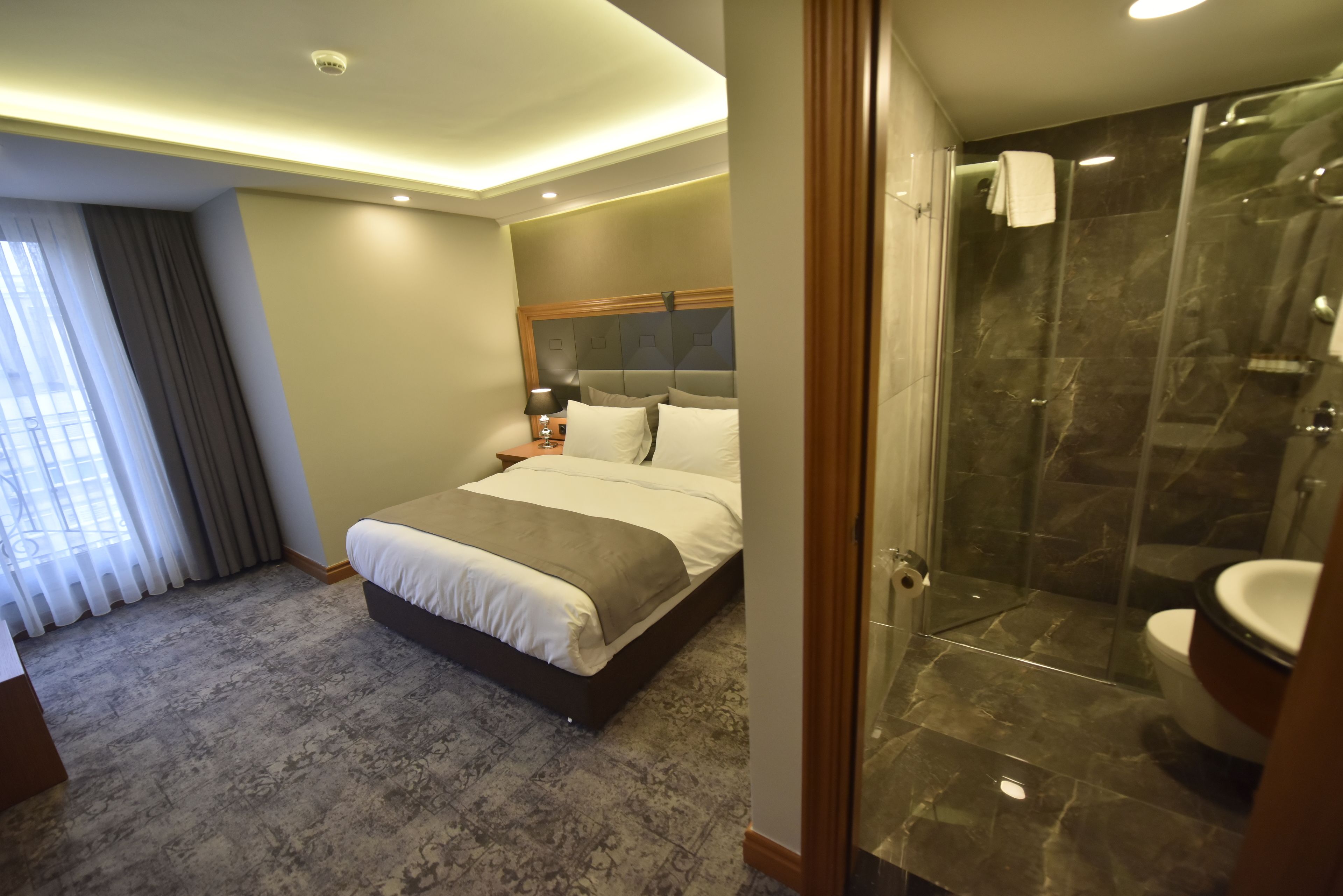 A hotel room with a bed, a shower, and a bathroom.