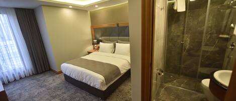 A hotel room with a bed, a shower, and a bathroom.
