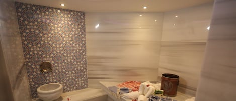 A bathroom with a patterned tile wall, a toilet, a bathtub, and a shower area.