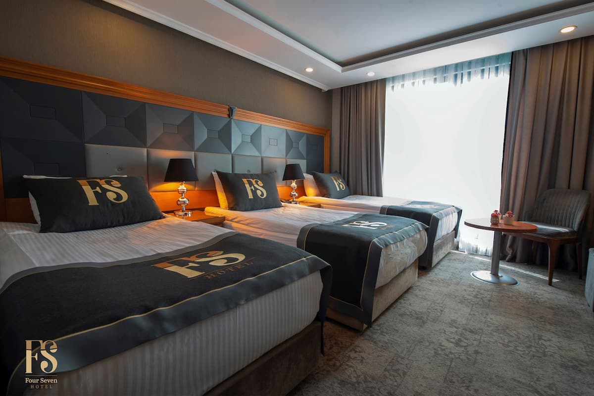 Hotellihuone, jossa on kaksi sänkyä, pieni pöytä ja tuoli.