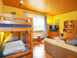 A room with bunk beds, a television, a dining table, and a sofa. - Vacation apartment 1 - Uns Klausing (Heringsdorf)