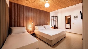Ein Schlafzimmer mit zwei Betten, Holzwandverkleidung, einem Nachttisch mit Lampe und einem Spiegel.